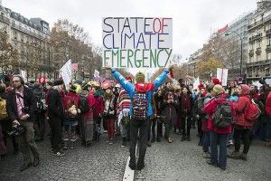 ETI02. Paris (France), 12/12/2015.- A demonstrator holds a poster stating 'State of Climate Emergency' behind indigenous people during a protest as the COP21 reaches its end in Paris, France, 12 December 2015. The 21st Conference of the Parties (COP21) is held in Paris from 30 November to 12 December aimed at reaching an international agreement to limit greenhouse gas emissions and curtail climate change. (Protestas, Francia) EFE/EPA/ETIENNE LAURENT